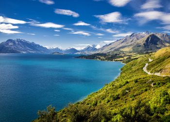 Summer view of Lake Wakatipu and the road from Queenstown to Glenorchy.  Southern Alps mountains in the distance.